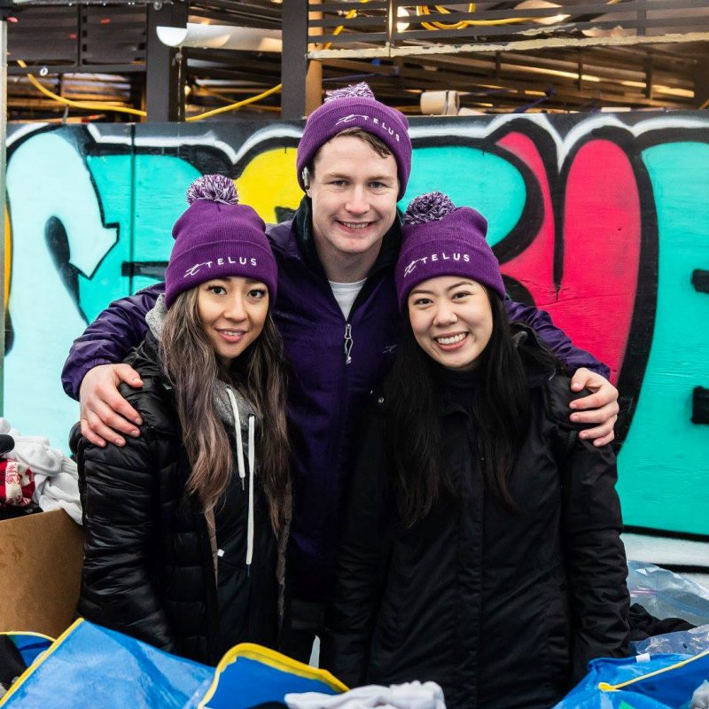 3 volunteers in purple hats pose together at the Street Store 5.0